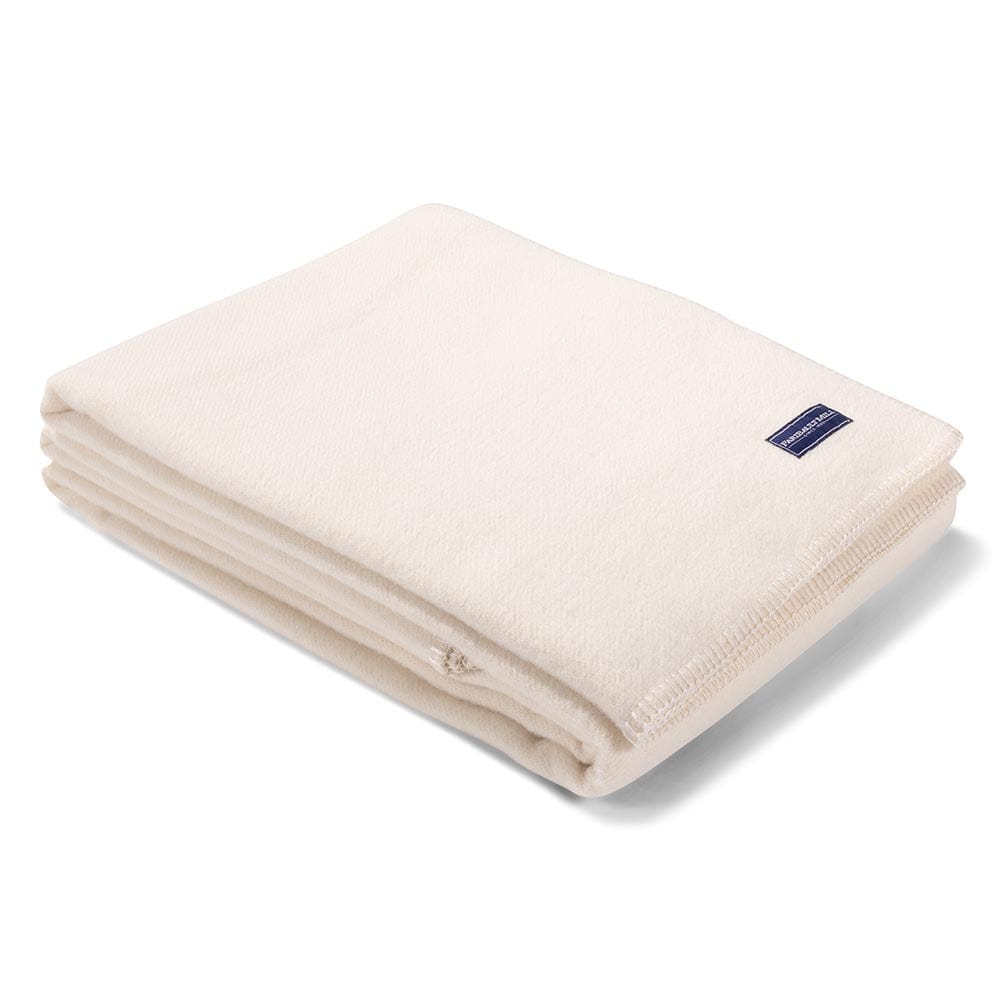 Faribault Mill Pure and Simple bone white middleweight wool bed blanket, folded and displayed at an angle to highlight the thickness, loft of the wool, and whipstitched edges.