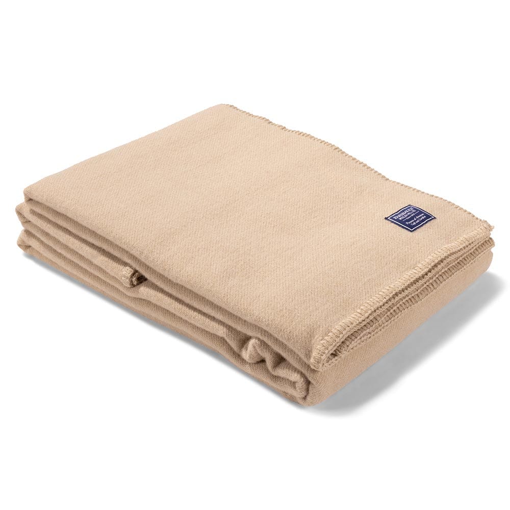 Faribault Mill Pure and Simple camel middleweight wool bed blanket, folded and displayed at an angle to highlight the thickness, loft of the wool, and whipstitched edges.