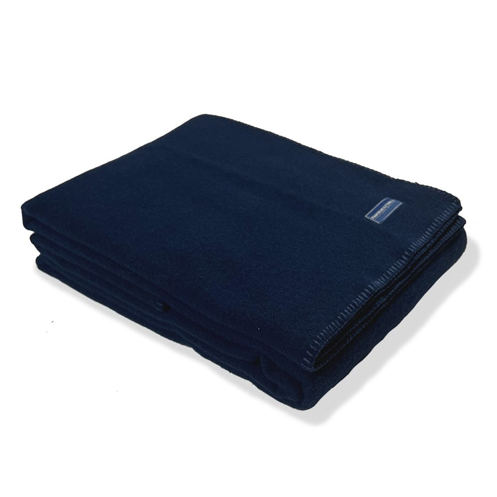 Faribault Mill Pure and Simple navy middleweight wool bed blanket, folded and displayed at an angle to highlight the thickness, loft of the wool, and whipstitched edges.