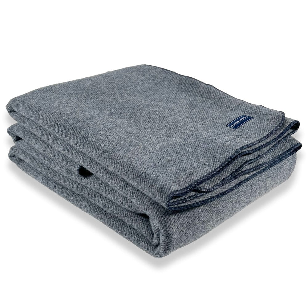 Faribault Mill Summit navy heavyweight wool bed blanket, folded and displayed at an angle to highlight the thickness, loft of the wool, and serged edges.
